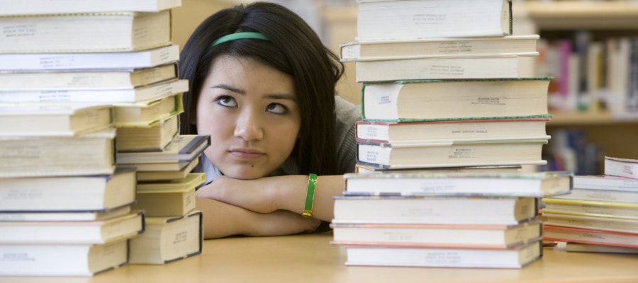 School girl looking at stacks of books in library