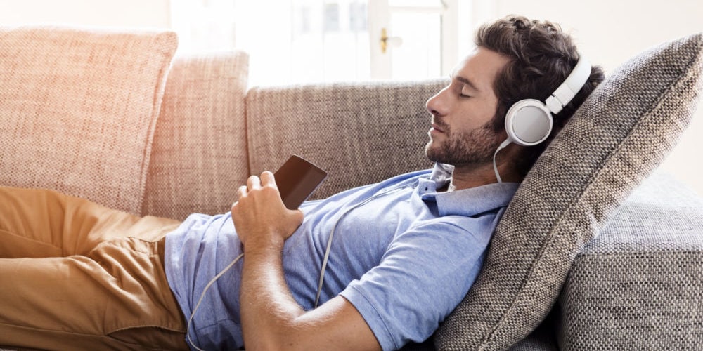 Man on his sofa listening to music with a smartphone