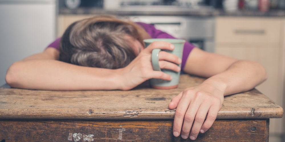 Tired woman with tea in kitchen