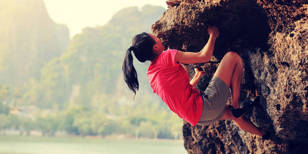 Young woman rock climber climbing at seaside mountain rock