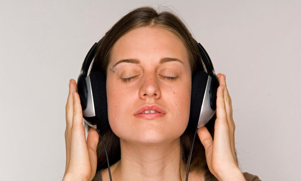 Young woman intently listening to music on headphones.