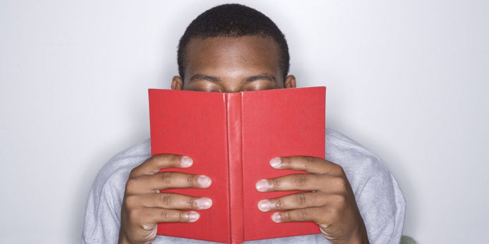 Young man reading a book in the library