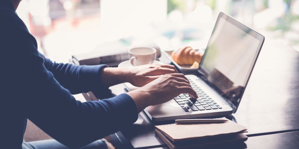 Freelancer working on laptop when having breakfast